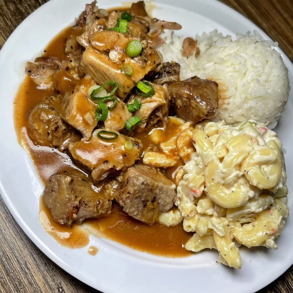 Hawaiian plate lunch with chicken adobo, white rice, and macaroni salad on a white plate.