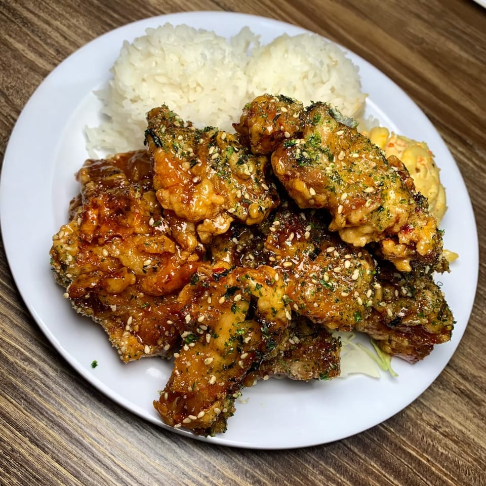 Hawaiian-style crispy chicken with a sweet glaze, sesame seeds, and herbs, served with white rice.