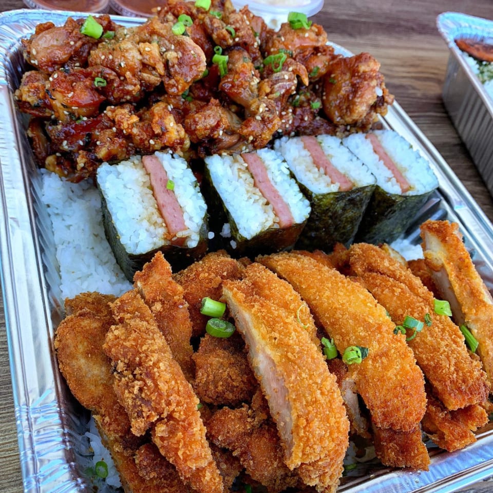 A Hawaiian platter with crispy fried chicken, spam musubi, and breaded pork cutlets over rice.